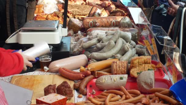 OLOMOUC, REPÚBLICA CHECA, 29 DE FEBRERO DE 2019: Mercado con productos de estabulación, matanza de cerdos, salchichas domésticas tradicionales, multitud de personas comprando, pesa la carne de salchicha a escala, salchicha — Vídeos de Stock