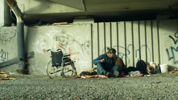OLOMOUC, REPUBBLICA CECA, 24 OTTOBRE 2018: Autentico gruppo emotivo di senzatetto e una sedia a rotelle invalida senza gambe sotto un ponte dove dormono, Europa — Video Stock