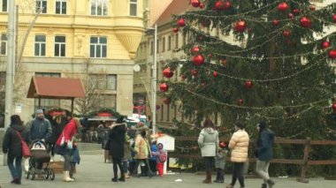 Brno, Çek Cumhuriyeti, 21 Aralık 2018: Noel ağacı aydınlık ve güzel süslenmiş şişeler kırmızı xmas topu, bebek çocuk ile bebek arabası ile insanlar aile baba ve anne parlar
