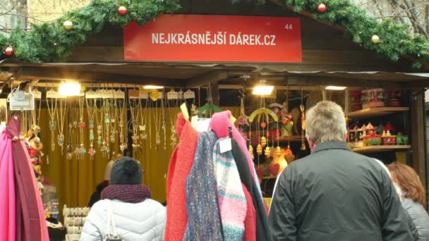 BRNO, RÉPUBLIQUE TCHÈQUE, 21 DÉCEMBRE 2018 : Les gens au marché de l'Avent de Noël sur la place, vente de cadeaux de produits en bois et de jouets pour enfants, écharpes et pendentifs d'hiver — Video