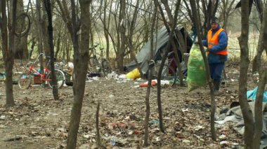 Olomouc, Çek Cumhuriyeti, 2 Ocak 2019: Adam çöp nad çöp toplamak çanta toplar, tehlike altındaki doğada orman manzara, insan çöp siyah dökümü, çarşaf evsiz getto çadır