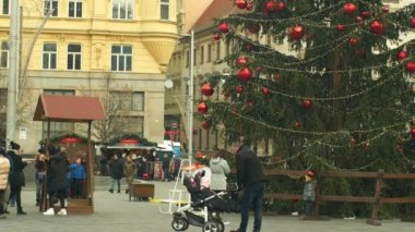Brno, Çek Cumhuriyeti, 21 Aralık 2018: Noel ağacı aydınlık ve güzel süsler ve şişeler kırmızı xmas topu ile süslenmiş parlar, bebek çocuk ile bebek arabası ile insanlar aile babası