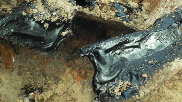 Токсичний дьоготь асфальтової хімії в деталях і крупним планом глини. Колишні відходи від відходів, вплив природи від забрудненого грунту та води хімікатами та нафтою, чорний бітум перероблений синтетичний матеріал — стокове відео