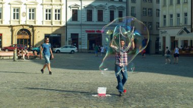 Olomouc, Çek Cumhuriyeti, 11 Haziran 2019: Çubuklarda deterjan sabunu ve ipi kullanarak baloncuk yapmak, büyük baloncuk, sokak sanatları adamı rüzgar sokak yapar ve para dileniyor, sabunlu sanatçı