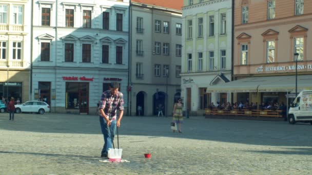 Olomouc, Tsjechië, 11 juni 2019: het maken van bubbels met wasmiddel zeep en touw op eetstokjes, grote bubbel, straatkunst man wind voert straat en smeken geld, zeep performer — Stockvideo