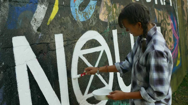 Aktivista nő festékek és újrafestése szimbólum kihalás Lázadás a jogi falon graffiti, cselekvési demonstráció az éghajlatváltozás ellen, a fiatalok — Stock Fotó