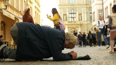 Prag, Çek Cumhuriyeti, 9 Eylül 2019: Evsiz dilenci turistler beyzbol şapkasına para basıyor ve parayı yeniden hesaplıyor, diz çöküp dileniyor.