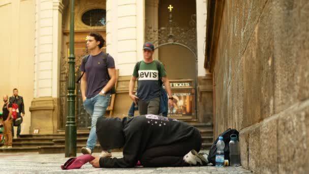 Прага, Чехія, 9 вересня 2019 р.: безпритульна дівчина благає туристів кидати монети в шапку, поліцейський ловить незаконний вчинок, прохає милостиню з розпростертим жебраком. — стокове відео