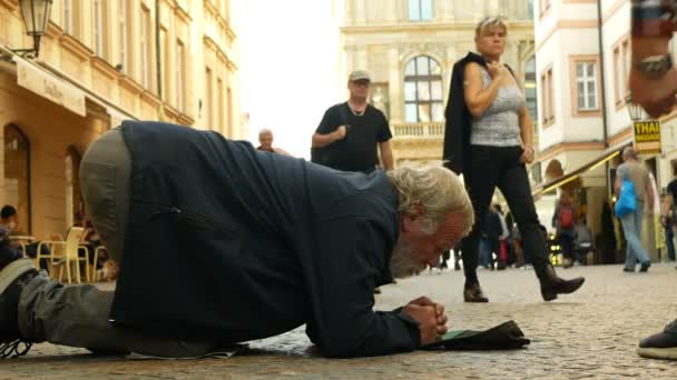 Prague, Czech Republic, September 9, 2019: Άστεγοι ζητιάνοι τουρίστες ρίχνουν χρήματα νομισμάτων στο καπέλο του μπέιζμπολ και υπολογίζει εκ νέου τα χρήματα, ικετεύει ελεημοσύνη γονατίζοντας ή γονατίζοντας τη ζωή του δρόμου αυθεντικό ζητιάνος — Αρχείο Βίντεο