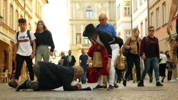 PRAGUE, REPÚBLICA CHECA, SETEMBRO 9, 2019: Sem-teto implorando turistas asiáticos jogar dinheiro moeda em boné de beisebol e recalculates dinheiro, esmolas implora ajoelhar-se ou ajoelhar-se rua vida autêntica — Vídeo de Stock