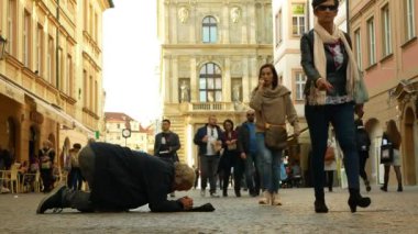 Prag, Çek Cumhuriyeti, 9 Eylül 2019: Evsiz dilenci Asyalı turistler beysbol şapkasına bozuk para atıyor ve para hesaplıyor, diz çöküp diz çöküp dileniyorlar.