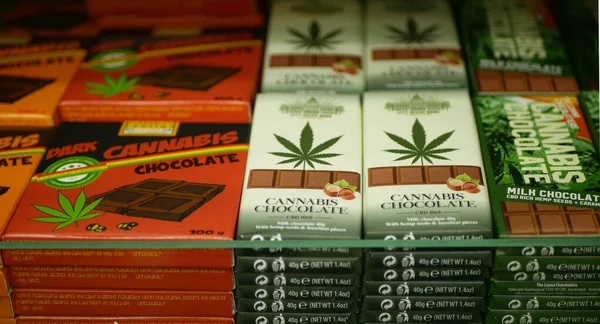 Cannabis chocolade winkel of winkel Praag, verpakt hennep cannabidiol Cbd cacao Rick zaden en donker in verlicht pijn, blad symbool, plank melk noten met suiker,, onkruid goederen te koop — Stockfoto