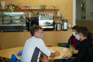 PRAGUE, CZECH REPUBLIC, 22 Temmuz 2020: Coronavirus cafe restoranı maskesi aile yemekleri, çocuk atıştırmalıkları, alışveriş merkezi süpermarketi, salgın solunumu olan 19 kişi