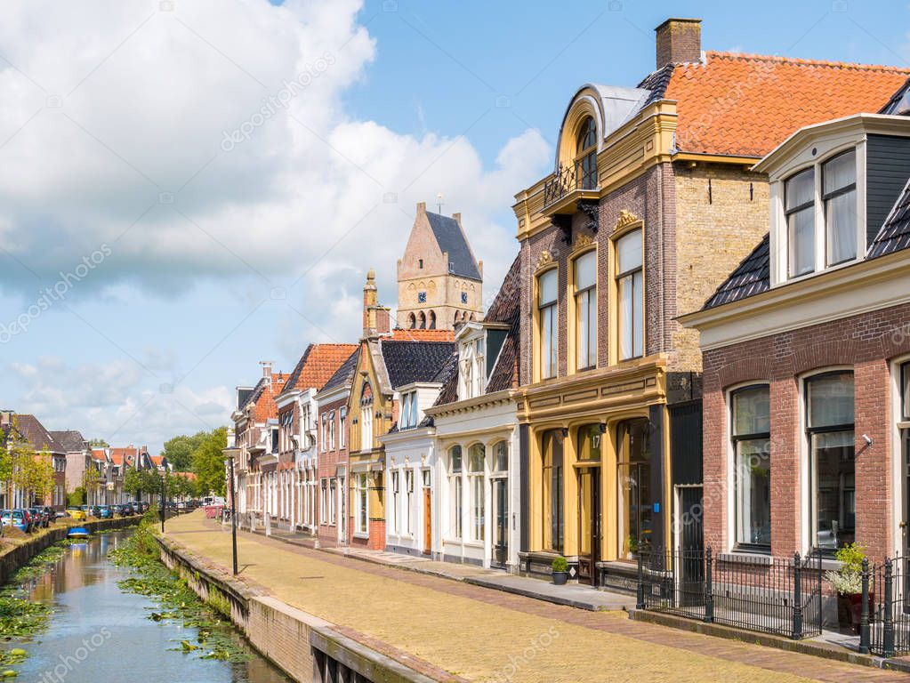 Street scene of Kleine Dijlakker canal and tower of protestant church in old town of Bolsward, Friesland, Netherlands