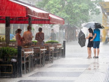 Şiddetli yağmur barınma insanlar ve şemsiye şehir Buenos Aires, Arjantin ile çift