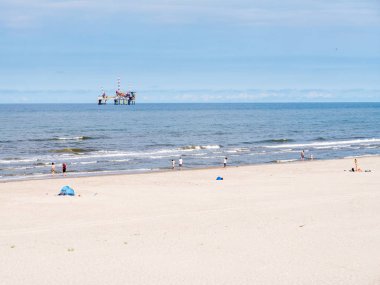 Ameland, Hollanda - 27 Ağustos 2017: İnsanlar plaj ve Kuzey Denizi ile offshore sondaj platformu, Frizce Adası Ameland, Friesland, Hollanda