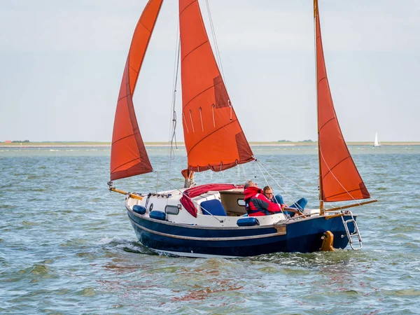 WADDENSEA, NETHERLANDS - AUG 23, 2017: People sailing on sailboat on Wadden Sea near coast of West Frisian island Ameland, Friesland