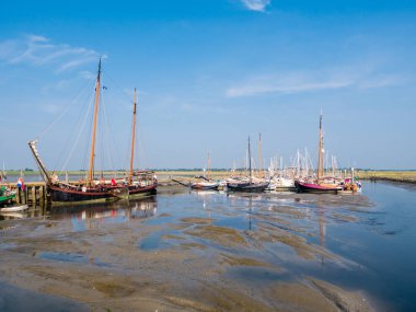 SCHIERMONNIKOOG, NETHERLANDS - AUG 29, 2017: Sailing boats in marina at low tide, West Frisian island Schiermonnikoog, Netherlands