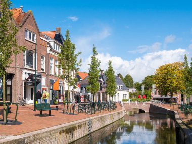 Dokkum, Hollanda - 12 Eylül 2017: Dokkum, Friesland, Hollanda'nın eski kentinde dükkanlar ve kanalla rıhtımda yürüyen insanlar