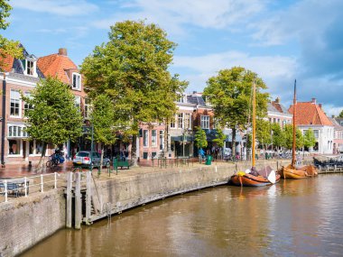 DOKKUM, NETHERLANDS - SEP 12, 2017: People and shops on quayside of historic harbour in old town of Dokkum, Friesland, Netherlands