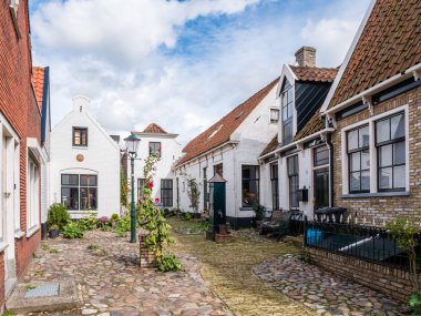 DEN BURG, NETHERLANDS - SEP 8, 2018: Historic courtyard Hofje with old white houses and water pump in Weverstraat of Den Burg town on Texel island