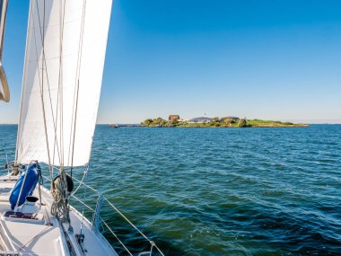 Sailboat sailing to fort island Pampus on IJmeer lake near Amsterdam, Netherlands
