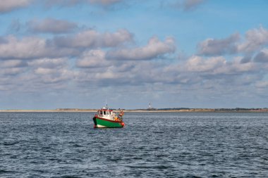 Wadden Denizi, Almanya - 24 Ağustos 2023: Amrum kıyısı ve deniz feneri yakınlarında küçük bir teknede balık tutan insanlar, Kuzey Frizya, Holstein-Holstein