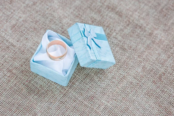 Wedding ring on blue jewelry box on linen background