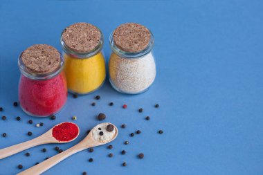 Mavi zemin üzerine baharat ve tahta kaşık ile bankalar