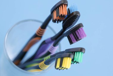 Mavi zemin üzerinde cam içinde çok renkli diş fırçaları seti