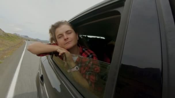 Молодая женщина торчит из окна машины на ветру — стоковое видео
