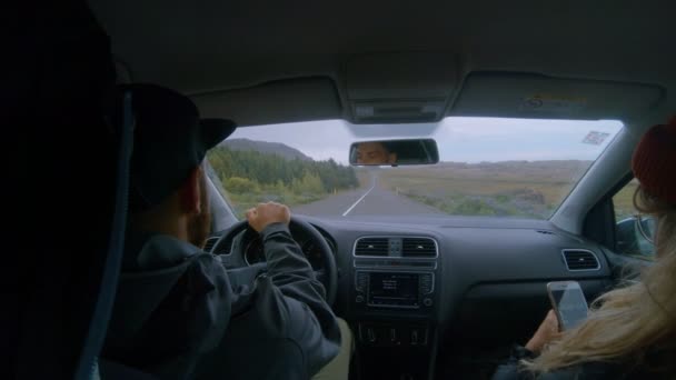 Молодая пара водит машину в Айсленде, использует приложение телефона — стоковое видео