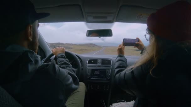 Pareja joven conduce un coche en iceland, utiliza la aplicación del teléfono — Vídeo de stock