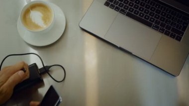 Düz dizüstü bilgisayar ve kahve latte sanat Kupası ile minimalist tablonun video yatıyordu, adam onun ölü suçlayın ya da smartphone, Kuru için harici pil paketi veya güç banka bağlı enerji kaynağı kalmak alır