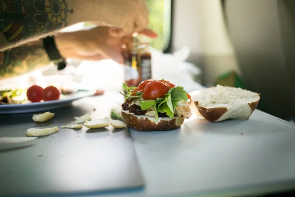 Man prepares burger during camping van trip — Stock Photo, Image