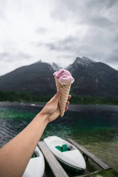 Женщина держит мороженое на берегу озера в горах — стоковое фото