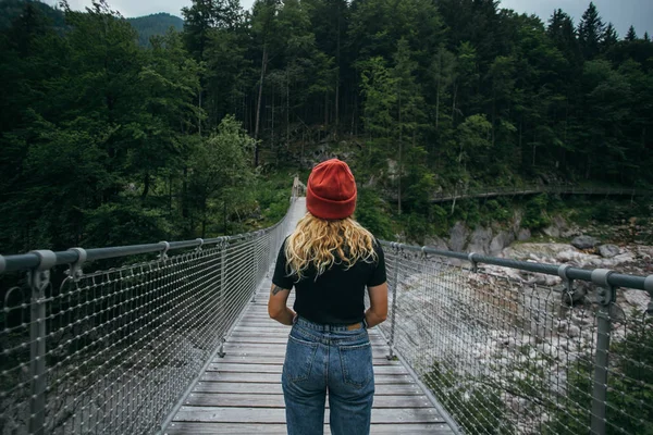 Young hiker woman walks on suspension bridge — Stock Photo, Image