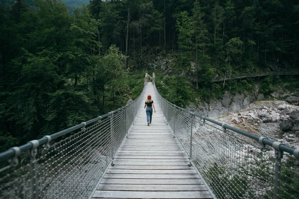 Young hiker woman walks on suspension bridge — Stock Photo, Image