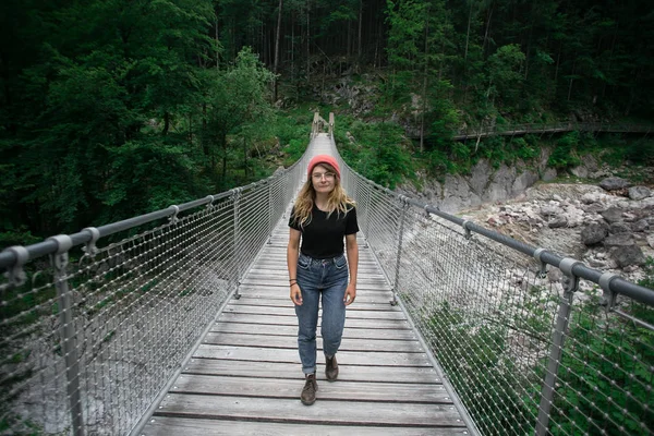 Jovem caminhante mulher caminha na ponte suspensa — Fotografia de Stock