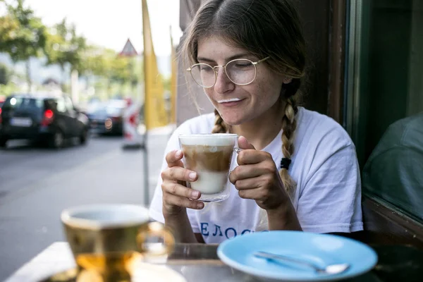 Cute pretty young woman drinks coffee milk foam — Stock Photo, Image