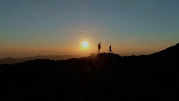 Ζευγάρι βόλτες στην κορυφή του βουνού ή οικόσημο στο ηλιοβασίλεμα — Αρχείο Βίντεο