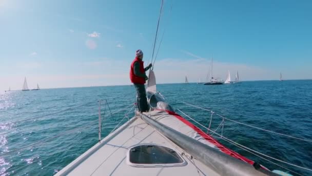 Skipper or sailor stands on deck nose of yacht — Stock Video