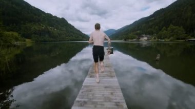 Genç adam çalışır ve göl alp suya atlar