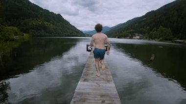 Genç adam çalışır ve göl alp suya atlar