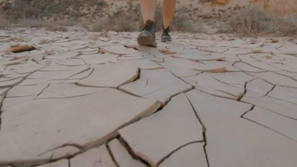 Kvinna i läderstövlar går på torr djupgående jord — Stockvideo