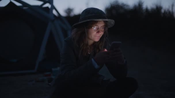 Joven acampada al lado de la tienda utiliza smartphone — Vídeos de Stock
