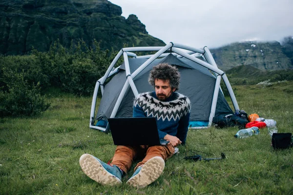 Freelance worker with laptop at camping site