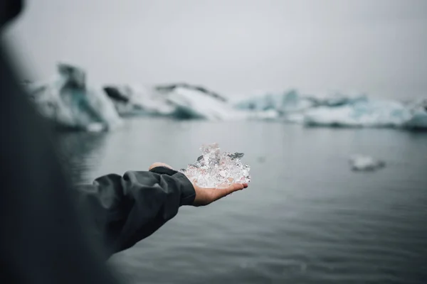 Explorer tourist holds melting ice block in ocean — Stock Photo, Image