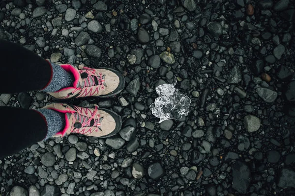 Wandelen laarzen naast ijsblok op zwarte strand — Stockfoto