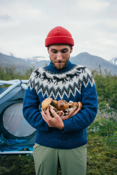 Young nomad hiker holds organic natural mushrooms
